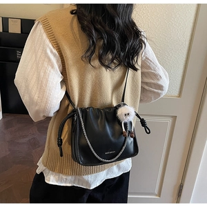 Détail du sac seau en cuir noir plissé avec chaîne argentée et porte-clés en peluche