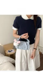 Light blue crossbody bag with pink floral embroidery and a white plush rabbit charm