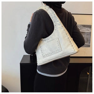 Detail of cream white rivet shoulder bag with vintage crackle leather texture on model