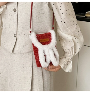 Detail of red knitted Christmas mobile bag with faux fur trim and handmade leather tag