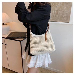 Detail of beige crochet hobo bag featuring hollow mesh pattern and brown leather tassel
