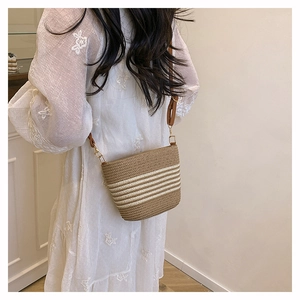 Detail of striped straw bucket bag showing woven texture and brown leather strap