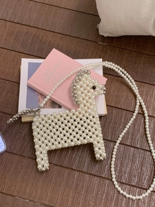 Handmade pearl beaded horse crossbody bag with silver accents on a wooden background