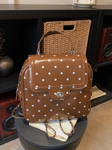 Vintage brown and white polka dot backpack with chain straps and metallic twist lock