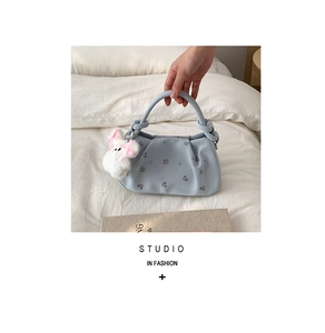 Detail of light blue floral dumpling bag with a cute plush bunny pendant and ring handle