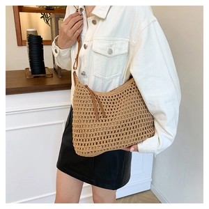 Detail of hollow-out crochet beach bag with adjustable brown leather shoulder strap