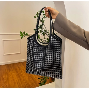 Detail showing hand-held black tote bag with shimmering white rhinestone grid pattern