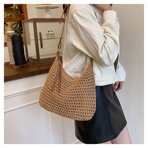 Detail of woven crochet shoulder bag with hollow mesh texture and brown tassel accent