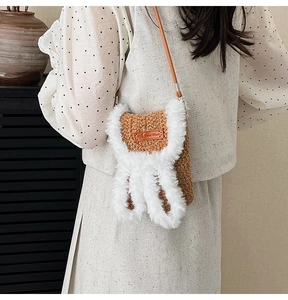 Close-up of brown knit crossbody bag with plush rabbit ears and Hand Made leather label