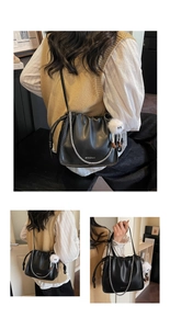 Détail d'un sac seau plissé noir avec chaîne argentée et charm de monstre en peluche