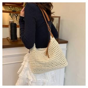 Detail showing beige crochet tote bag with brown leather strap and decorative fringe tassel