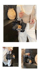 Detail of black tote bag with textured jacquard finish, metal clasp and bear charm