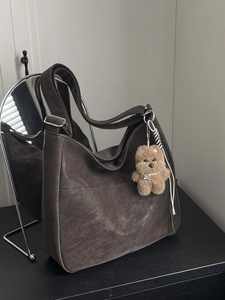 Deep brown suede large Hobo shoulder bag with a cute plush dog charm on a sleek desk