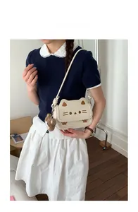Detail of cute cat-shaped crossbody bag with soft bear pendant in daily lifestyle use