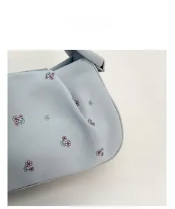 Detailed view of light blue leather bag with pink and green floral print patterns