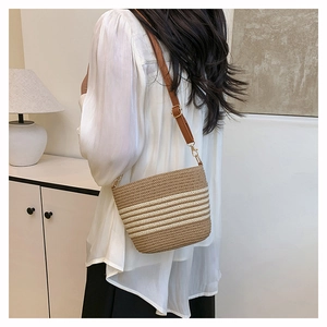 Detail of handwoven straw bucket bag with brown faux leather strap and striped texture