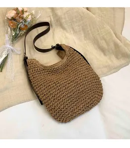 Close-up of woven straw tote bag with brown shoulder strap and fine texture details