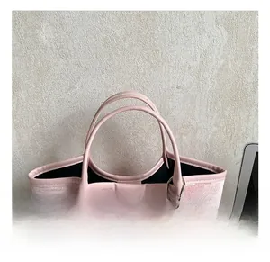 Detail of pink woven tote bag with round leather handles and bear pendant