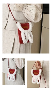 Detail of red knit bag with white faux fur rabbit ears and brown Hand Made leather label