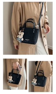 Détail d'un sac seau noir avec texte logo et pendentif ours en peluche blanc mignon