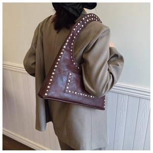 Detailed view of vintage cracked leather texture and silver rivets on the burgundy bag