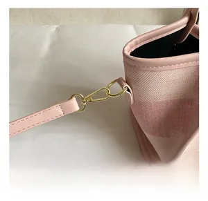 Detail of premium gold-tone metal hook and pink leather strap on a textured bucket bag