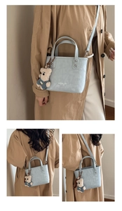Détail du sac cabas bleu clair avec lettrage de marque et breloque ours en peluche