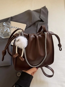 Deep brown leather crescent bag with chic pleats, silver chain, and cute plush charm