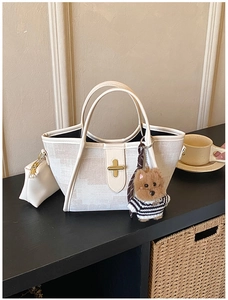 Detailed view of cream canvas tote bag with gold twist lock and a cute bear charm