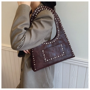 Detail of red-brown leather shoulder bag with vintage silver rivets and oily wax texture
