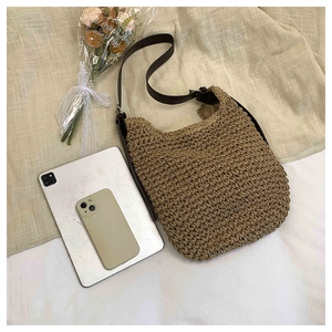 Detail view of woven straw shoulder bag showing large capacity for tablet and phone