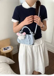 Detail view of light blue dumpling bag with floral embroidery and rabbit plush charm