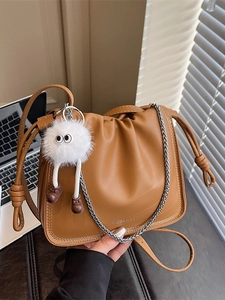 Brown leather ruched bucket bag with silver chain and cute monster charm accessory
