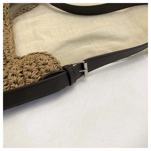 Close-up of woven tote bag showing dark brown leather strap with silver metal buckle