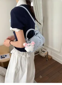 Detail of light blue crescent bag with floral embroidery and white plush dog charm