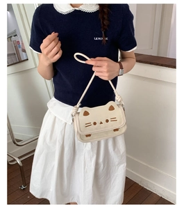Detail of cute cream cat-shaped handbag featuring 3D ears and embroidered facial details
