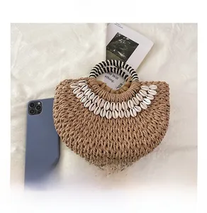 Vue détaillée d'un sac en paille avec décor en coquillages et poignée rayée sur tissu