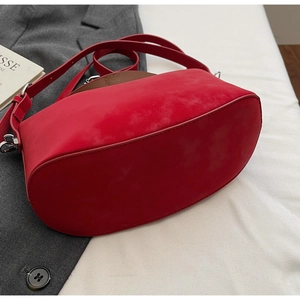 Detail of red suede handbag with oval base structure and silver metal buckles