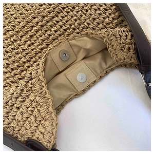 Detail of woven straw tote bag featuring magnetic closure and brown leather strap