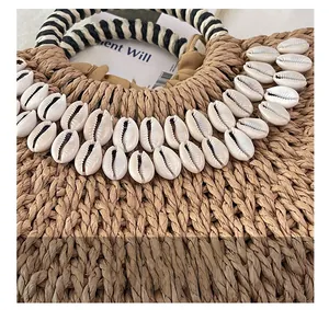 Détail du sac en paille fait main avec décorations de coquillages et anses rayées