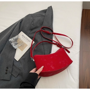 Detail of red suede crescent shoulder bag with silver hardware and adjustable strap