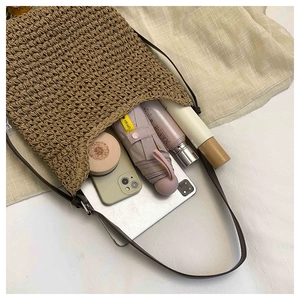 Macro detail of spacious woven tote showing phone, umbrella, and daily items inside