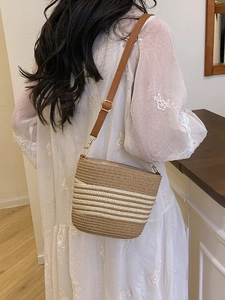 Straw bucket bag for women featuring white stripes and adjustable brown leather strap