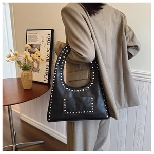 Close-up of black hobo shoulder bag with silver studs and decorative pocket detail