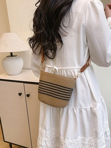 Chic straw bucket bag with black stripes and brown leather strap for beach vacations