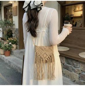 Primer plano de un bolso bandolera boho tejido con flecos en un ambiente de café al aire libre