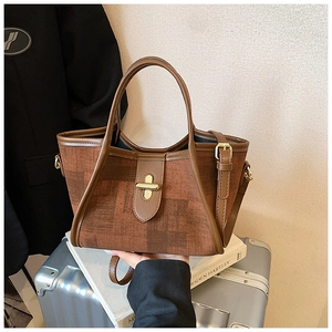 Detailed close-up of brown textured crossbody bag featuring vintage gold rotary metal clasp