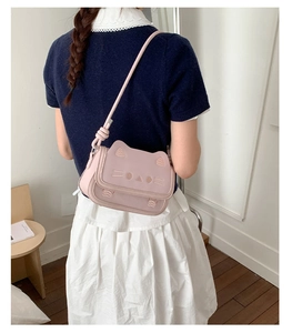 Rear view of model wearing a pink cat-shaped crossbody bag with embroidery details