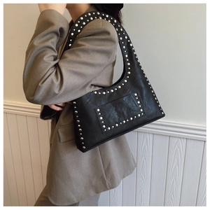 Detail of black motorcycle shoulder bag featuring silver rivet trim and crinkled texture
