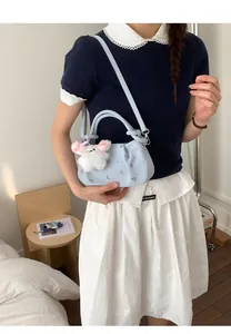 Detail of light blue floral embroidered handbag with cute white rabbit plush charm